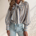 ZOFIA ATELIER ADRIANNA blouse with a large bow tie, long sleeves, and a striped floral pattern in blue, white, and pink.