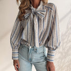 ZOFIA ATELIER ADRIANNA blouse with a large bow tie, long sleeves, and a striped floral pattern in blue, white, and pink.