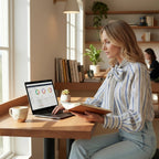 ZOFIA ATELIER ADRIANNA blouse with blue and white stripes, long sleeves, and a bow tie neck, worn by a woman working on a laptop.