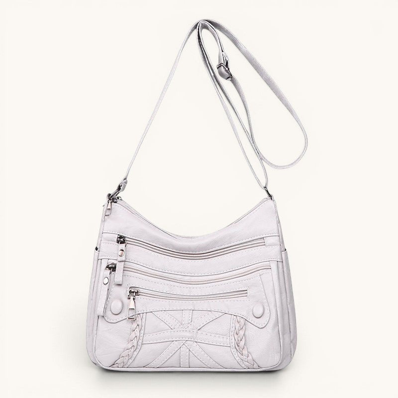 ZOFIA ATELIER AGNIESZKA white PU leather messenger bag with multiple zippered pockets and braided detail.
