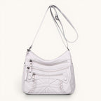 ZOFIA ATELIER AGNIESZKA white PU leather messenger bag with multiple zippered pockets and braided detail.