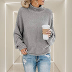 ZOFIA ATELIER ANNA grey chunky knit turtleneck sweater with ribbed cuffs and hem. Model holding coffee cup.