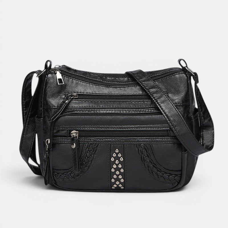 ZOFIA ATELIER black multi-layer PU crossbody bag with braided trim and stud embellishments.