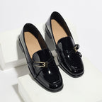 ZOFIA ATELIER black patent leather square toe loafers with gold buckle detail.
