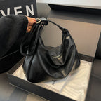 ZOFIA ATELIER black PU leather dumpling shape tote bag with single strap and zipper detail.
