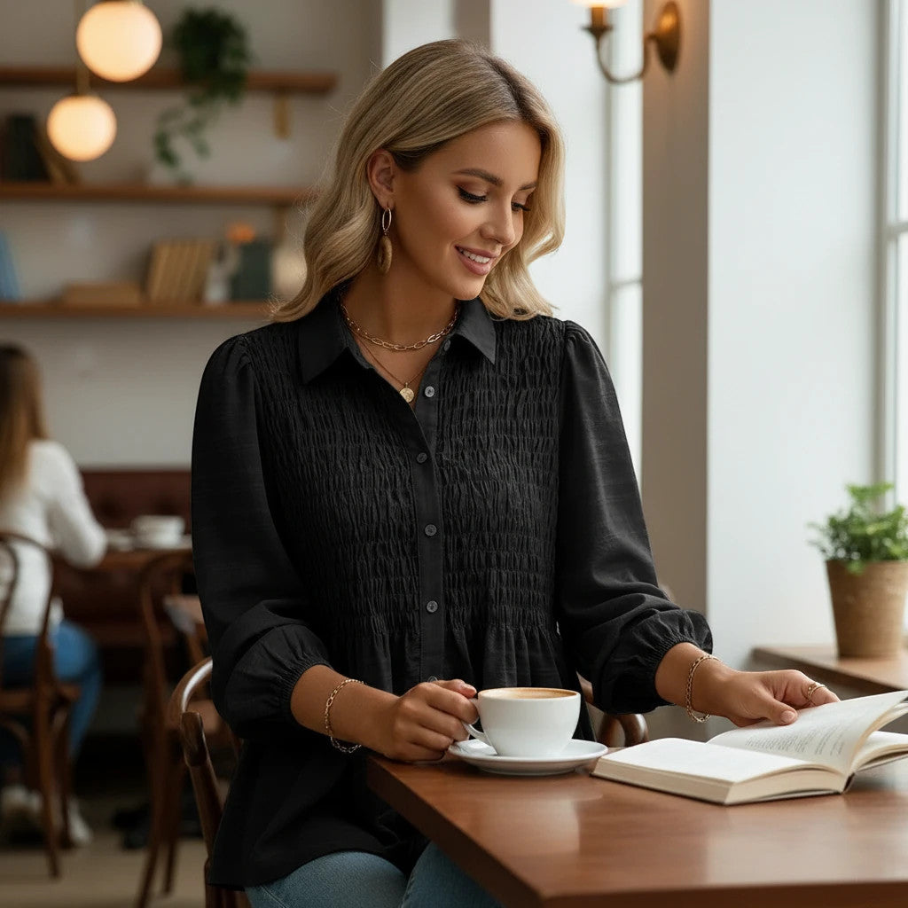 ZOFIA ATELIER black polyester button-down shirt with smocked front and puff sleeves, worn by a woman reading.