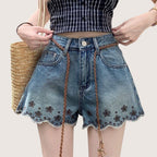 ZOFIA ATELIER blue denim shorts with embroidered flowers and frayed hem. Mid-rise waist, straight leg.