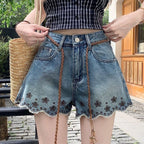 ZOFIA ATELIER blue denim shorts with embroidered flowers and frayed hem. Mid-rise waist with braided belt.