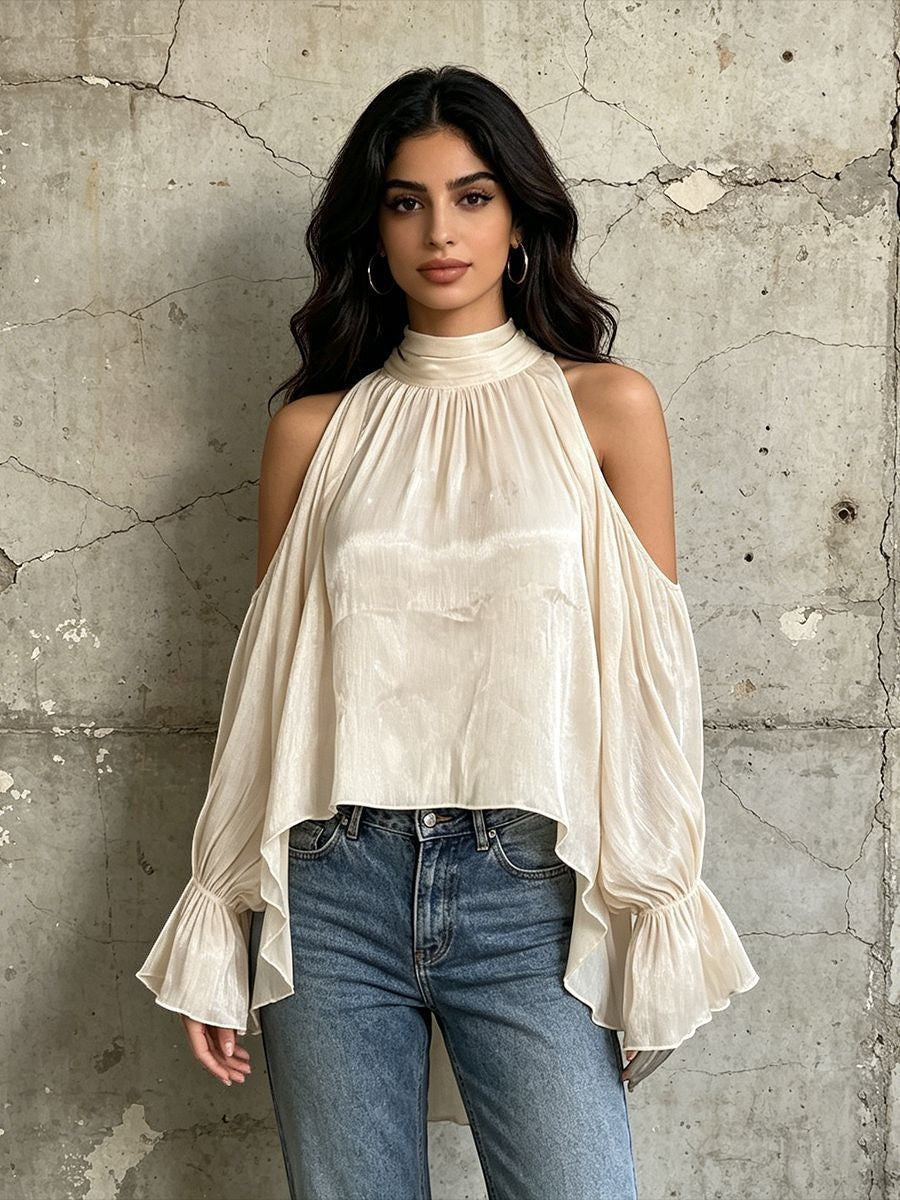 ZOFIA ATELIER cream cold-shoulder blouse with billowy sleeves and ruffled cuffs, paired with blue jeans.