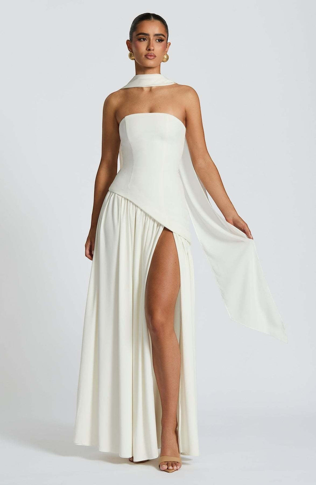 ZOFIA ATELIER off-the-shoulder tube dress in cream with a high slit and flowing scarf detail. Made of polyester.