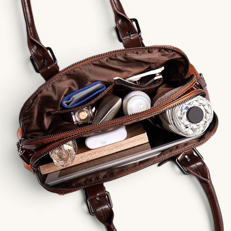 ZOFIA ATELIER Dominika brown leather messenger bag, open to show interior with books, umbrella, and cosmetics.