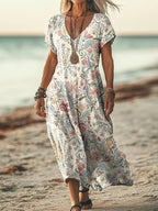 ZOFIA ATELIER Gabrysia floral V-neck midi dress with short sleeves and a flowing silhouette, worn on a beach.