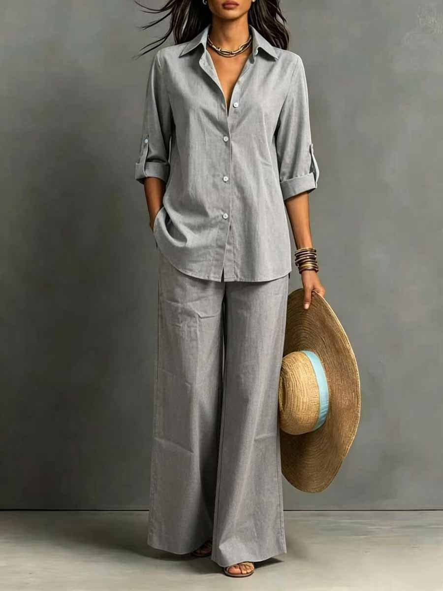 ZOFIA ATELIER grey cotton resort set with full-length pants and regular sleeve shirt. Model holds a wide-brimmed hat.