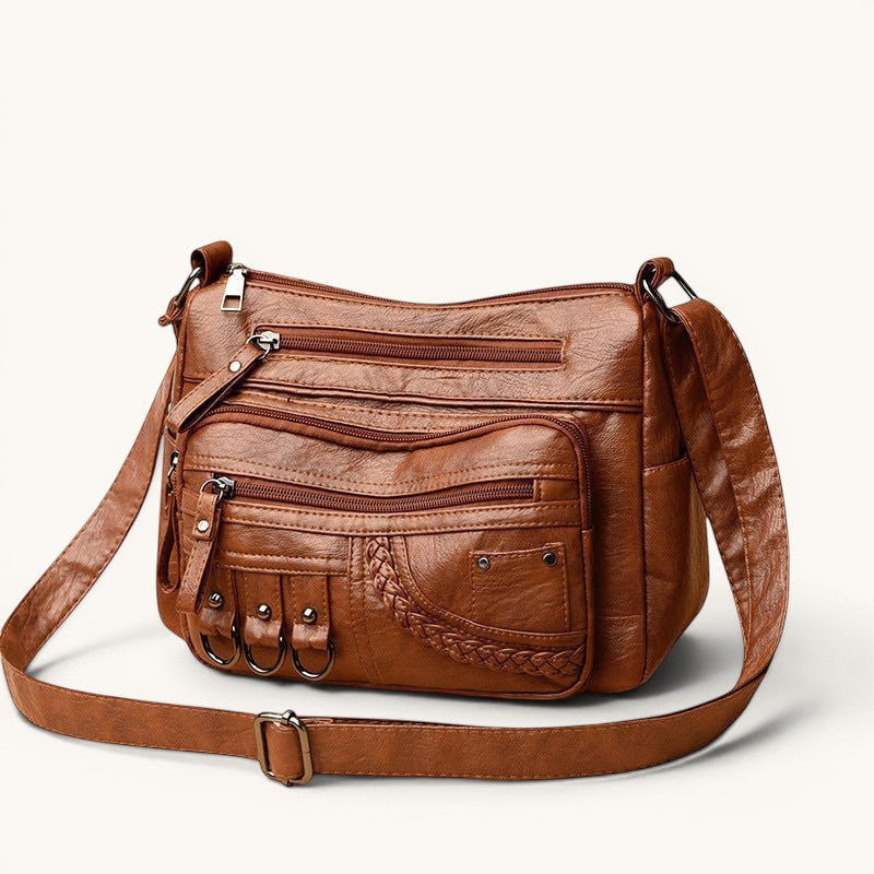 ZOFIA ATELIER Helena luxury crossbody bag in brown PU leather with multiple zippered pockets and braided detail.