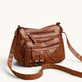 ZOFIA ATELIER Helena luxury crossbody bag in brown PU leather with multiple zippered pockets and braided detail.