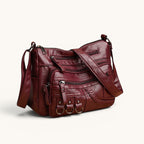 ZOFIA ATELIER Helena crossbody bag in burgundy PU leather with multiple zippered pockets and braided detail.