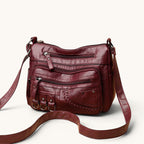 ZOFIA ATELIER Helena luxury crossbody bag in burgundy PU leather with multiple zippered pockets and braided detail.