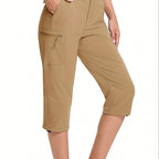 ZOFIA ATELIER MAGDA Asymmetric Waterproof Pants in Khaki. Lightweight, seven-quarter length, wide-leg flared pants with zippered cargo pocket.