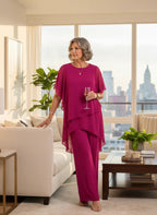 ZOFIA ATELIER MARINA chiffon suit set in rose red with quarter sleeves and trousers. Model holds champagne.