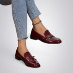 ZOFIA ATELIER Natalia patent square toe loafers in burgundy, featuring a gold buckle detail. Flat sole, slip-on style.