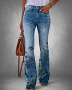 ZOFIA ATELIER light wash denim flare jeans with a vibrant floral and butterfly print on the legs.