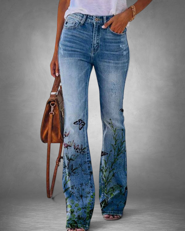 ZOFIA ATELIER light wash denim flare jeans with a vibrant floral and butterfly print on the legs.