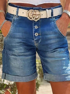 ZOFIA ATELIER RENATA high-waist denim crop shorts with rolled hem, button fly, and white belt with gold buckle.
