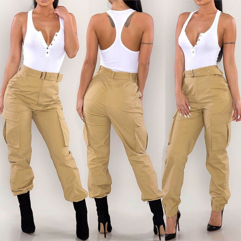 ZOFIA ATELIER tan slim-fit cargo overalls with high waist and zipper detail, paired with a white henley bodysuit and black heels.
