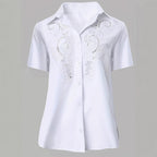ZOFIA ATELIER white short-sleeved blouse with intricate embroidered lace detail and hollow-out design. Made from polyester and rayon.
