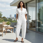 ZOFIA ATELIER white linen-blend jumpsuit with short sleeves, stand collar, and black buttons. Loose fit, wide-leg.