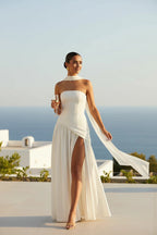 ZOFIA ATELIER white polyester off-the-shoulder tube dress with high slit and draped scarf detail.